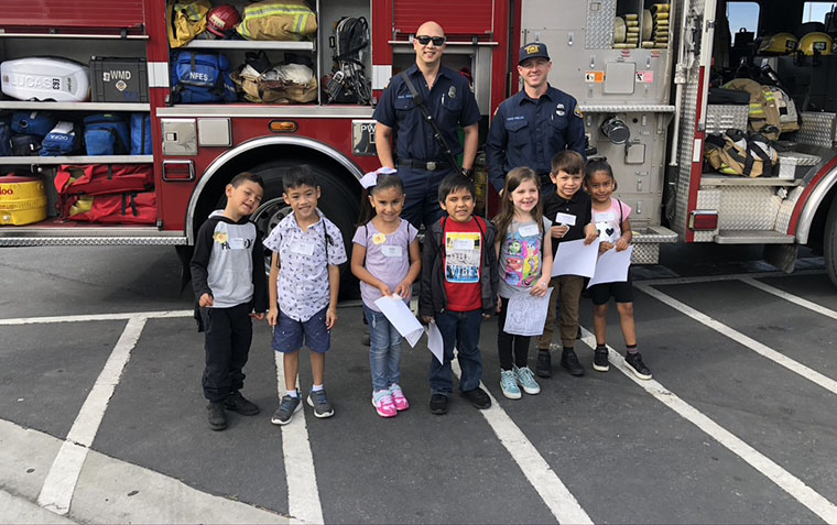 kids with firemen in front of fire truck